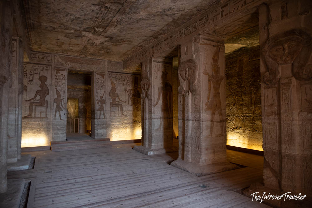 Dimly lit interior hall of Abu Simbel temple, with carved pillars, hieroglyphs, and deity reliefs