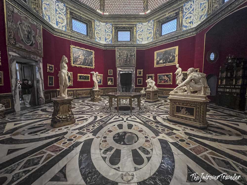 Octagonal Tribune room at the Uffizi Gallery Florence, with crimson walls, marble floor, and classical sculptures
