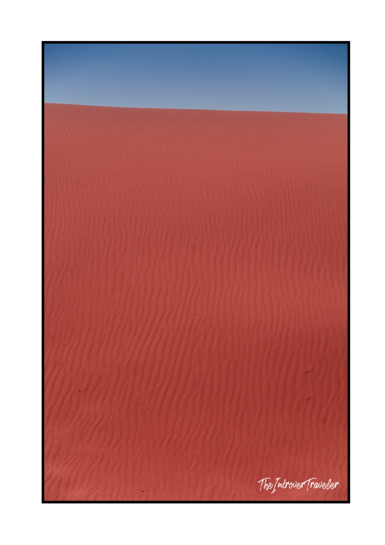 Rippled red sand dunes under clear blue sky in Wadi Rum desert, Jordan