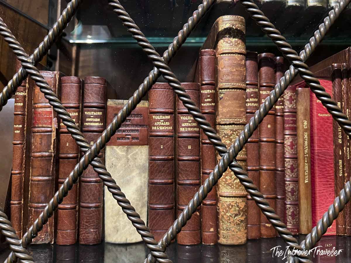 Antique leather-bound Voltaire volumes behind ornate iron grillwork at the Morgan Library, New York