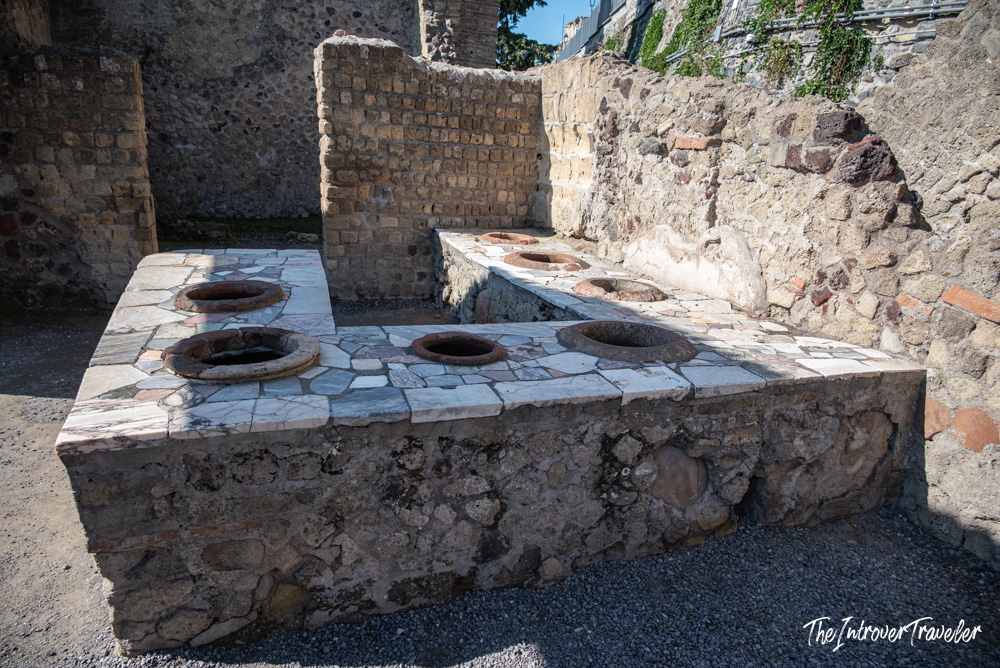 Ancient Roman thermopolium ruins at Herculaneum, with marble counter and sunken food vessels intact