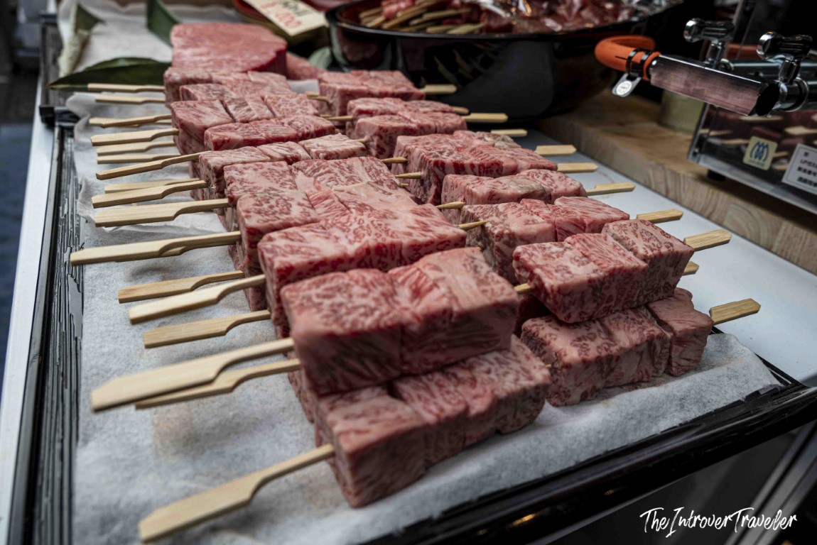 Raw Wagyu beef skewers with heavy marbling at a Tsukiji market food stall, Tokyo