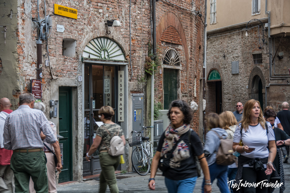 Busy street corner near the Anfiteatro Romano in Lucca, Tuscany, with tourists and a ristorante sign