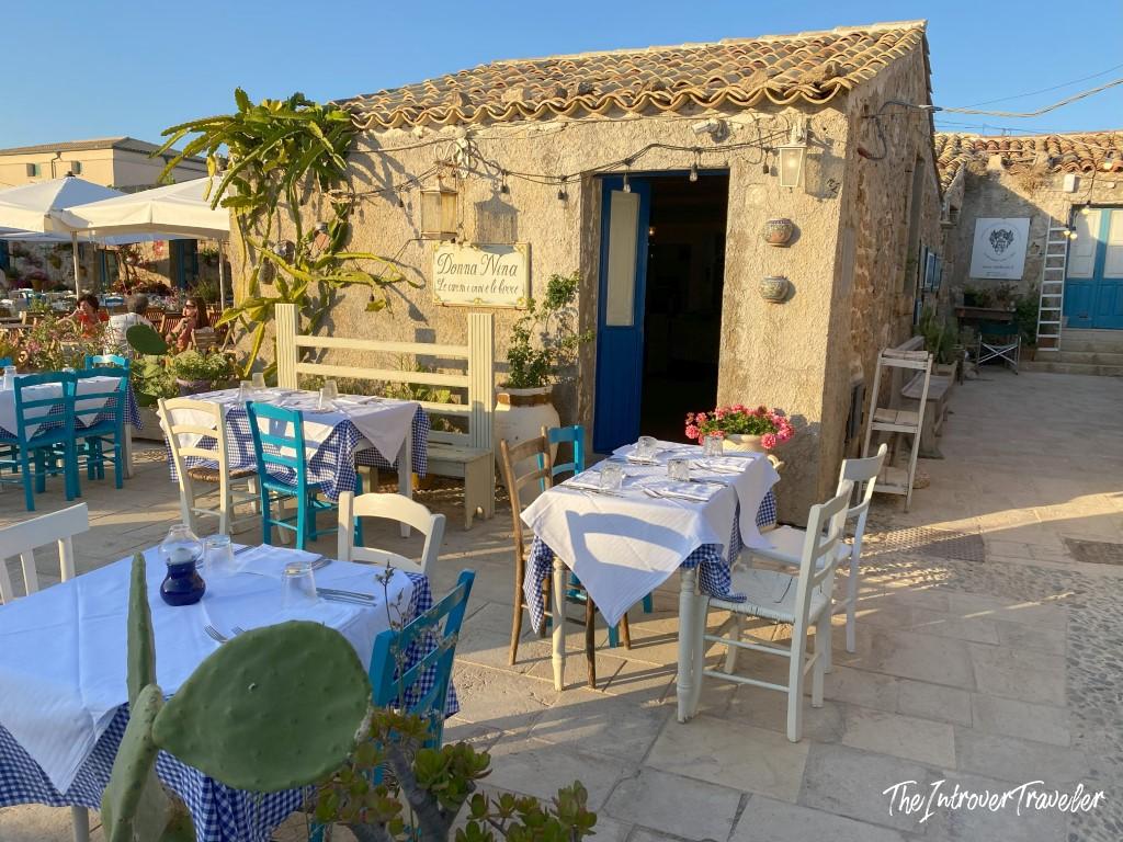 Donna Nina restaurant outdoor terrace in Marzamemi, Sicily, with blue and white tables