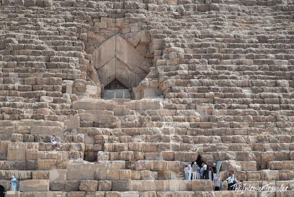 Close-up of the Great Pyramid of Giza entrance, with tourists at the base showing the massive stone blocks scale