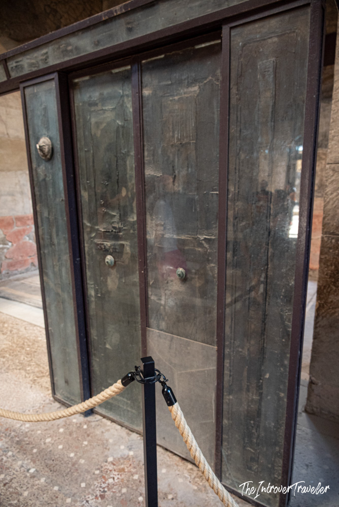 Ancient bronze door preserved at Herculaneum excavations, protected behind a rope barrier for visitors
