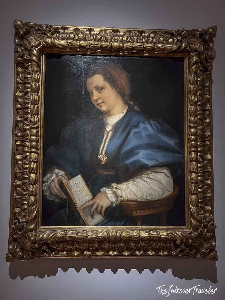 Portrait of a Girl with a Book by Andrea del Sarto, displayed in an ornate gold frame at the Uffizi Gallery Florence