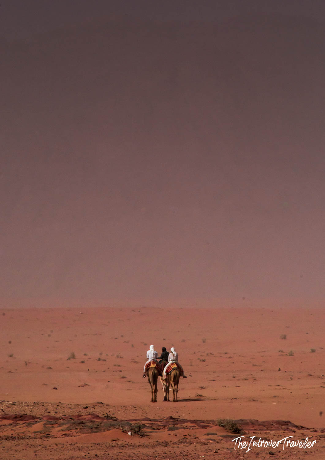 Two riders on camels crossing the vast red sands of Wadi Rum desert, Jordan