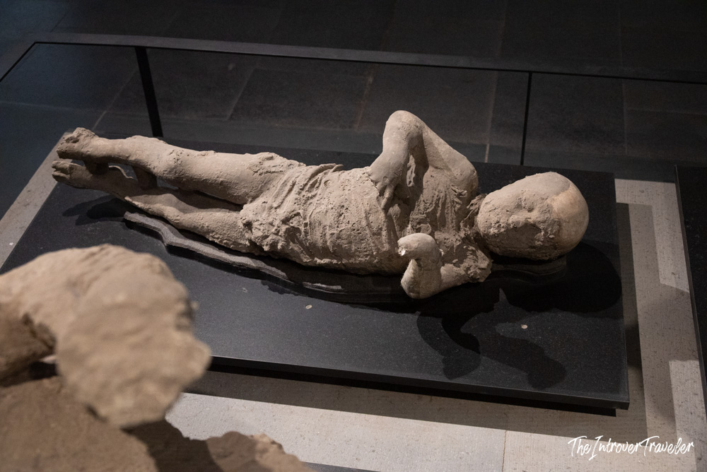 Plaster cast of a Pompeii victim preserved in volcanic ash, displayed in a glass case