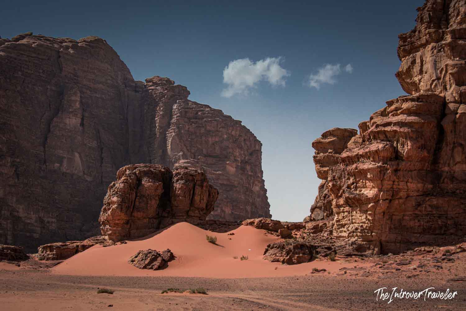 Red sandstone canyon walls and pink sand dunes in Wadi Rum, Jordan's iconic desert landscape