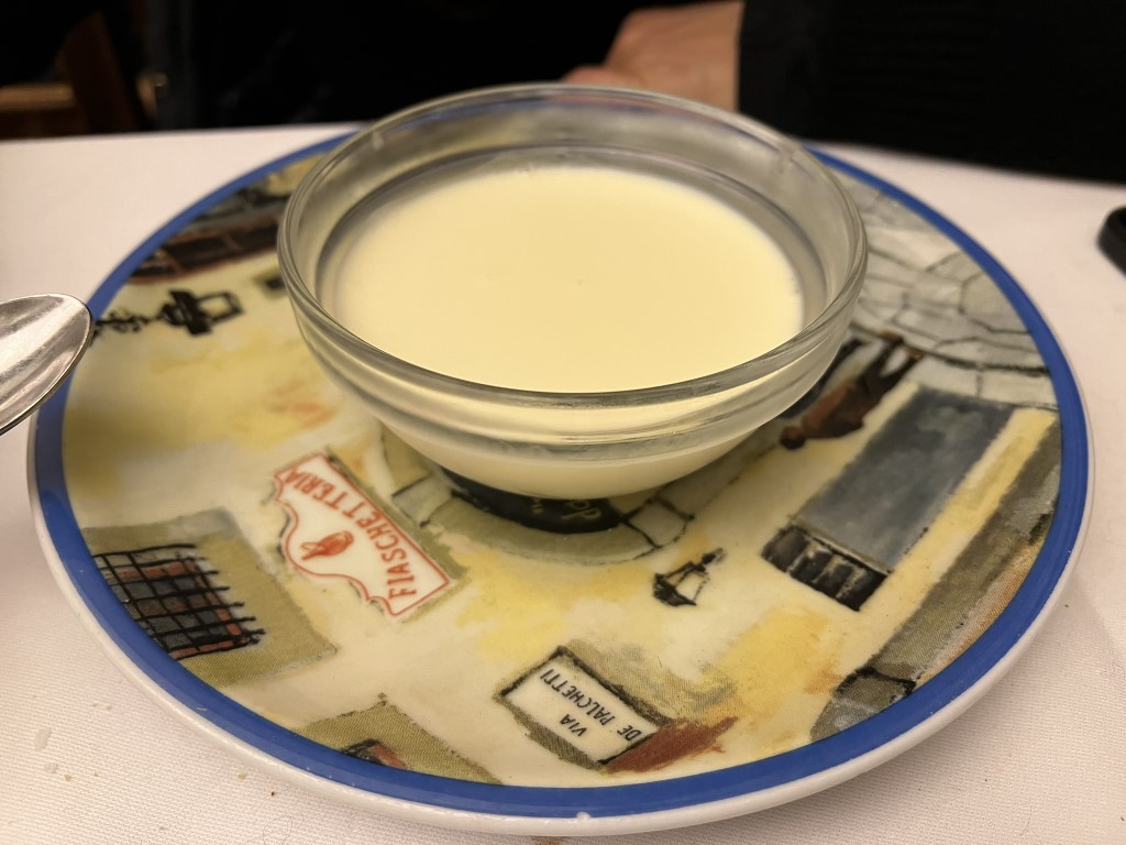 Creamy panna cotta dessert served at Trattoria Il Latini, Florence, on a decorative Florentine street-scene plate
