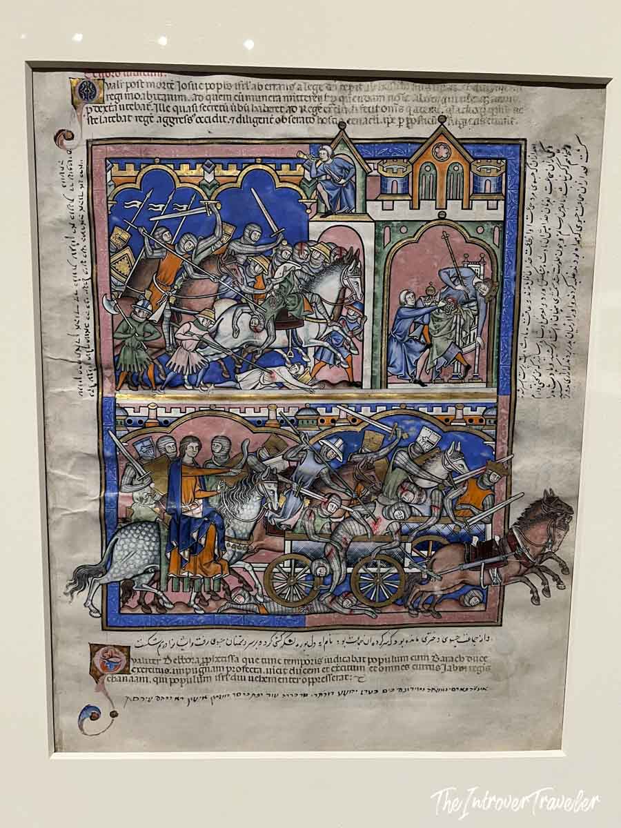 Illuminated medieval manuscript page with battle scenes, displayed at the Morgan Library Museum New York