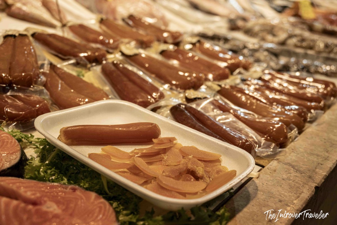 Bottarga (cured fish roe) displayed on a tray with slices at a coastal city fish market