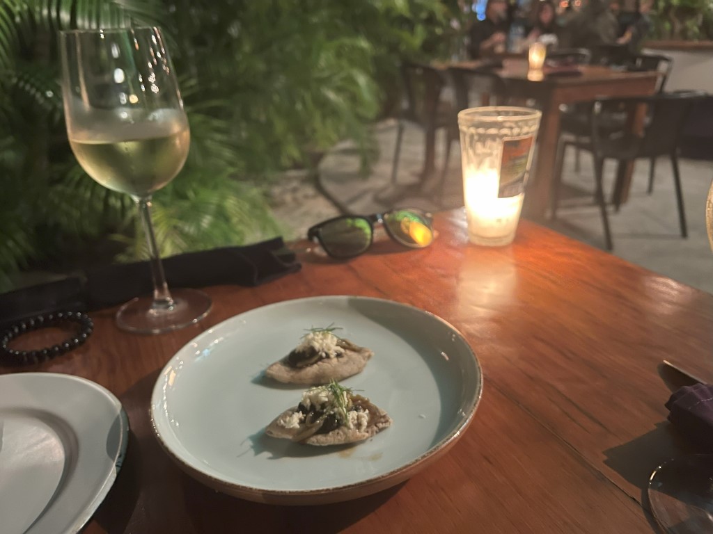 Two elegant tlayuditas topped with cheese and herbs at Kondesa, Cozumel, by candlelight