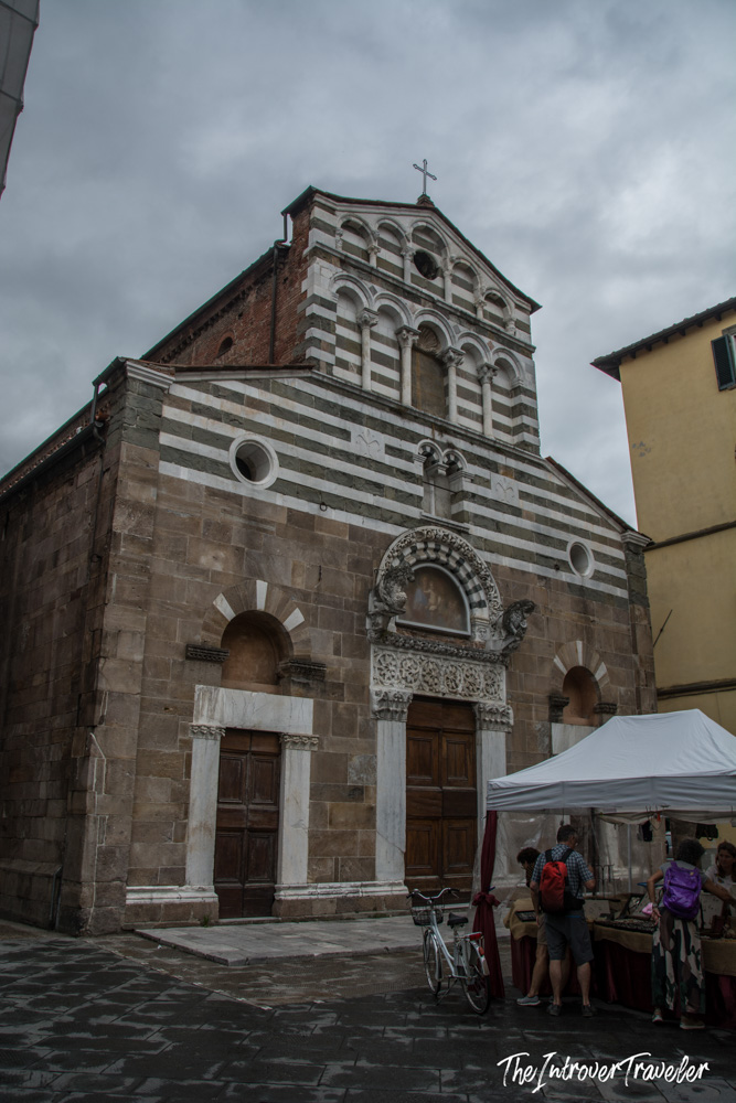 Romanesque church facade with green and white striped marble in Lucca, Tuscany, with market stalls outside