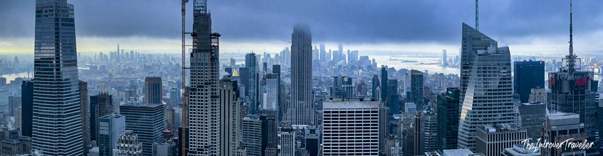 Panoramic Manhattan skyline view from Top of the Rock, with the Empire State Building shrouded in clouds