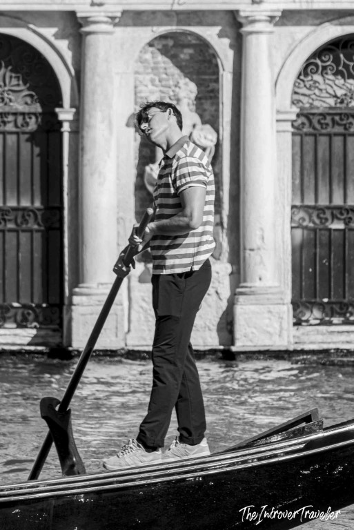 Gondolier rowing past ornate Venetian architecture near the Rialto, Venice
