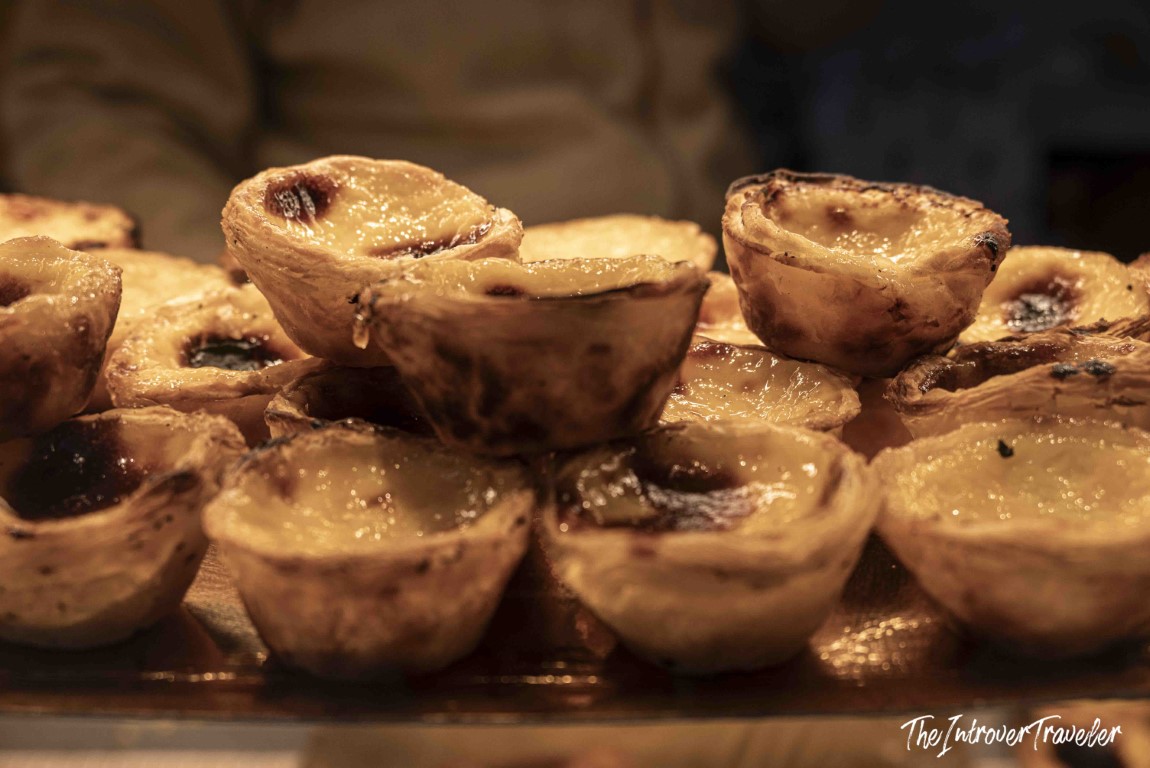 Freshly baked pasteis de nata stacked on a tray in Porto, with golden caramelized custard filling