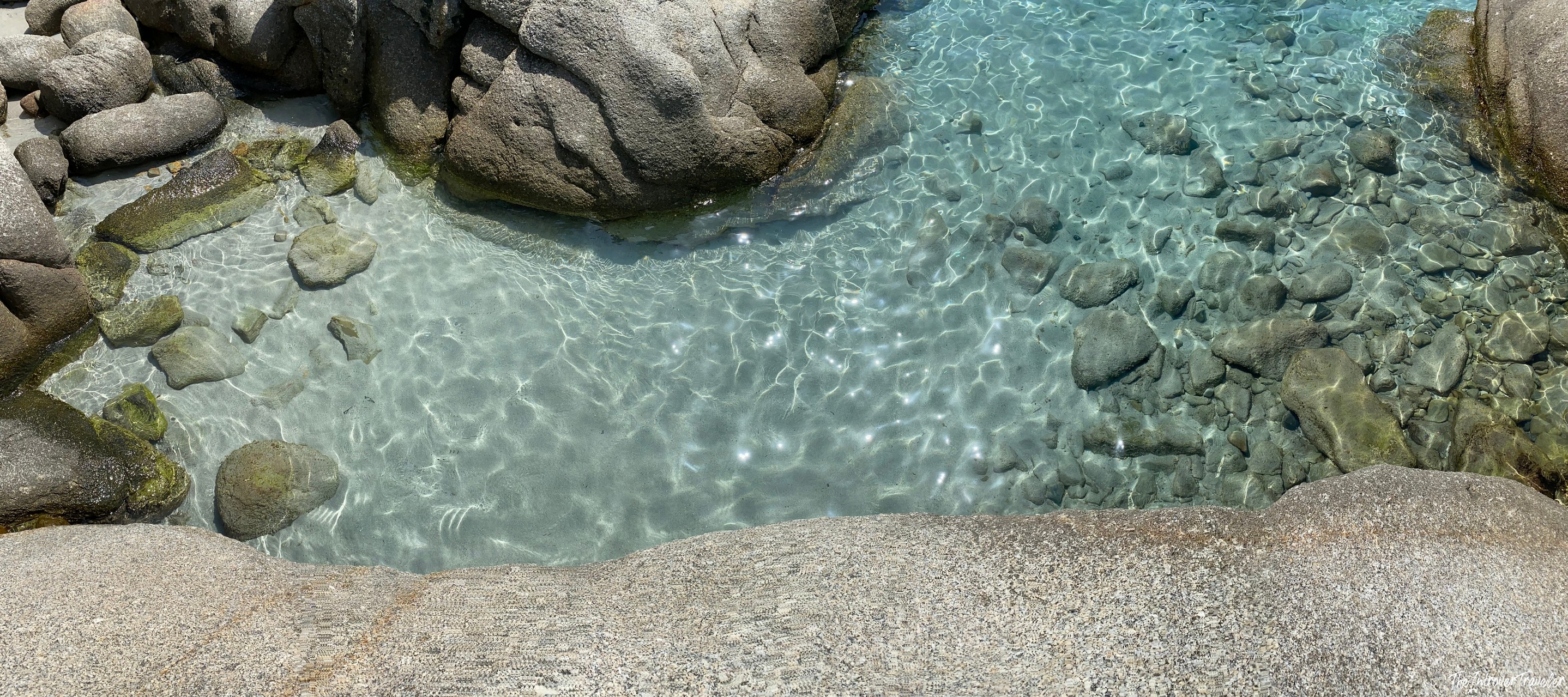 Crystal clear turquoise water between granite boulders at a secluded south Sardinia beach cove