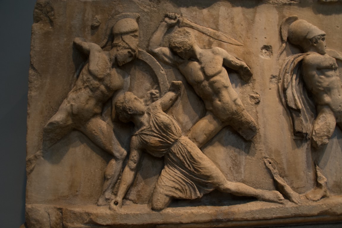 Ancient Greek battle relief at the British Museum, showing warriors and a fallen figure in combat