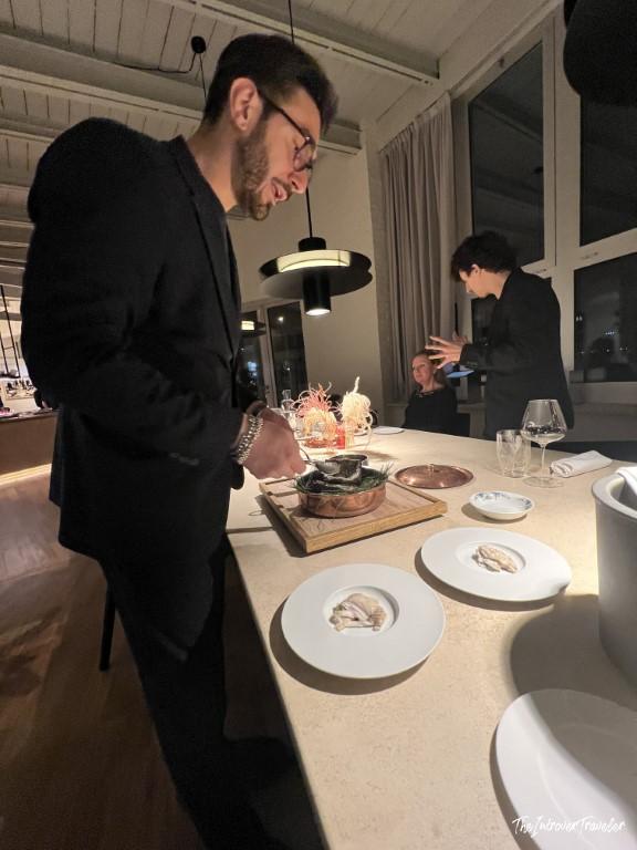 Chef plating an elaborate seafood tasting course at a fine dining restaurant in Rimini, Italy