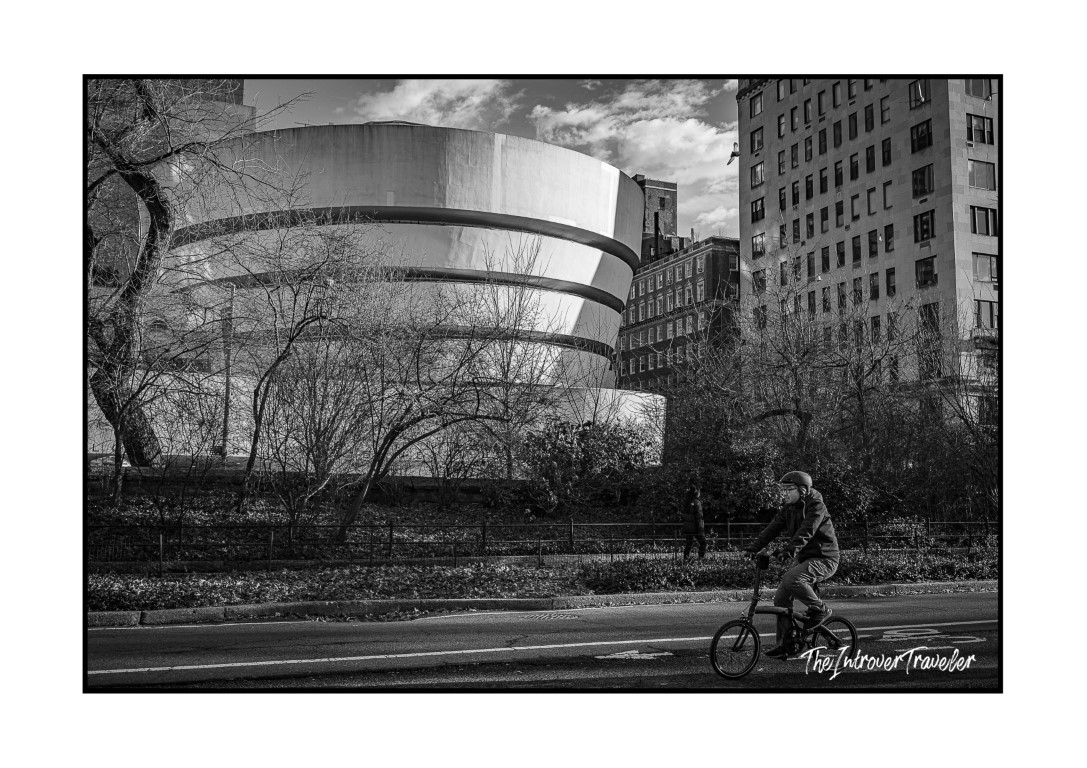 Cyclist riding past the Guggenheim Museum on Fifth Avenue, beside Central Park in New York