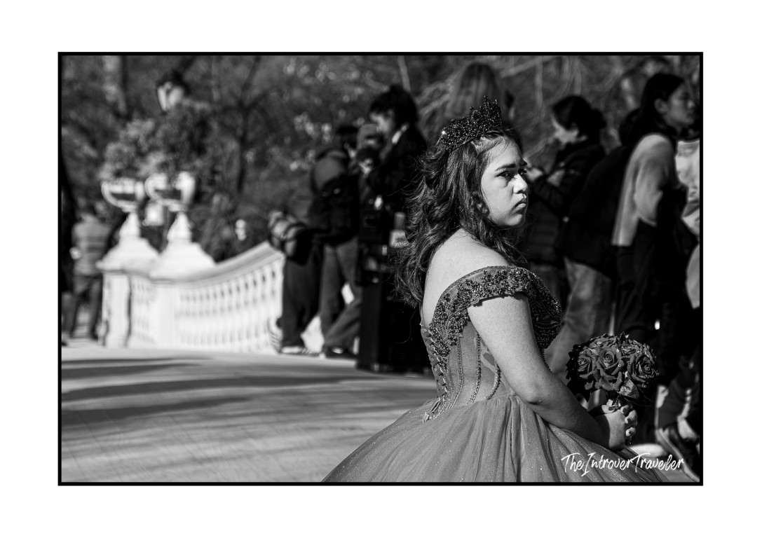 Young woman in quinceañera gown and crown holding roses at Central Park, New York