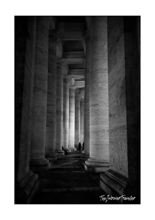 Black and white view through Bernini's colonnade columns at St. Peter's Square, Vatican City