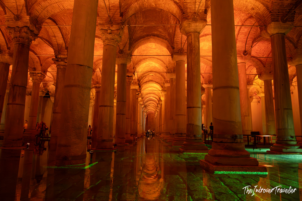 Interior of the Basilica Cistern in Istanbul, rows of ancient columns reflected in amber-lit water
