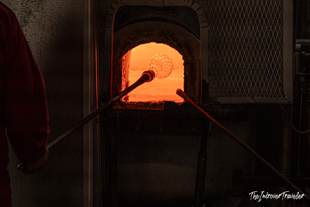 Molten glass on a blowpipe inside a glowing furnace at a Murano glassmaking workshop