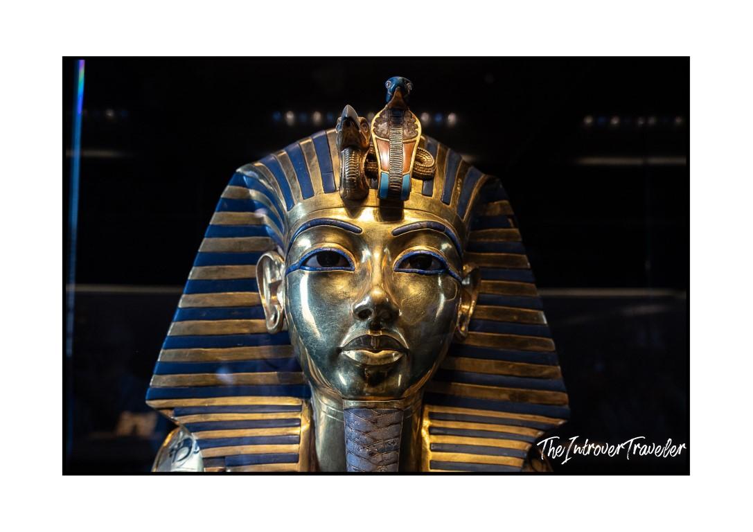 Gold funeral mask of Tutankhamun, iconic ancient Egyptian artifact with blue striped nemes headdress
