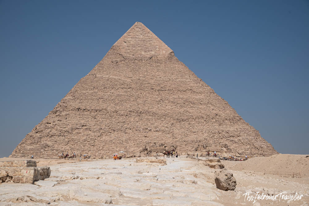 Pyramid of Khafre at Giza, with camels and visitors gathered at its base under a clear blue sky