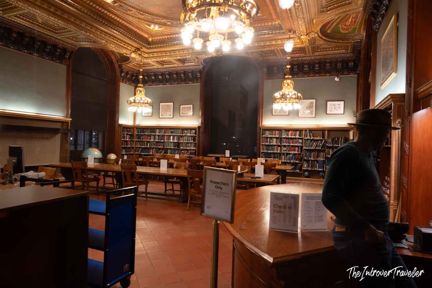 Interior of the New York Public Library research room, with ornate gold ceiling, chandeliers, and bookshelves