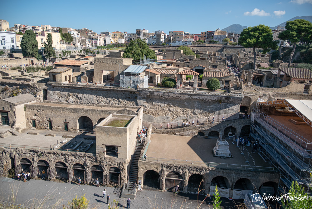 Aerial view of Herculaneum excavations, showing ancient Roman ruins, arched boat chambers, and modern Ercolano beyond
