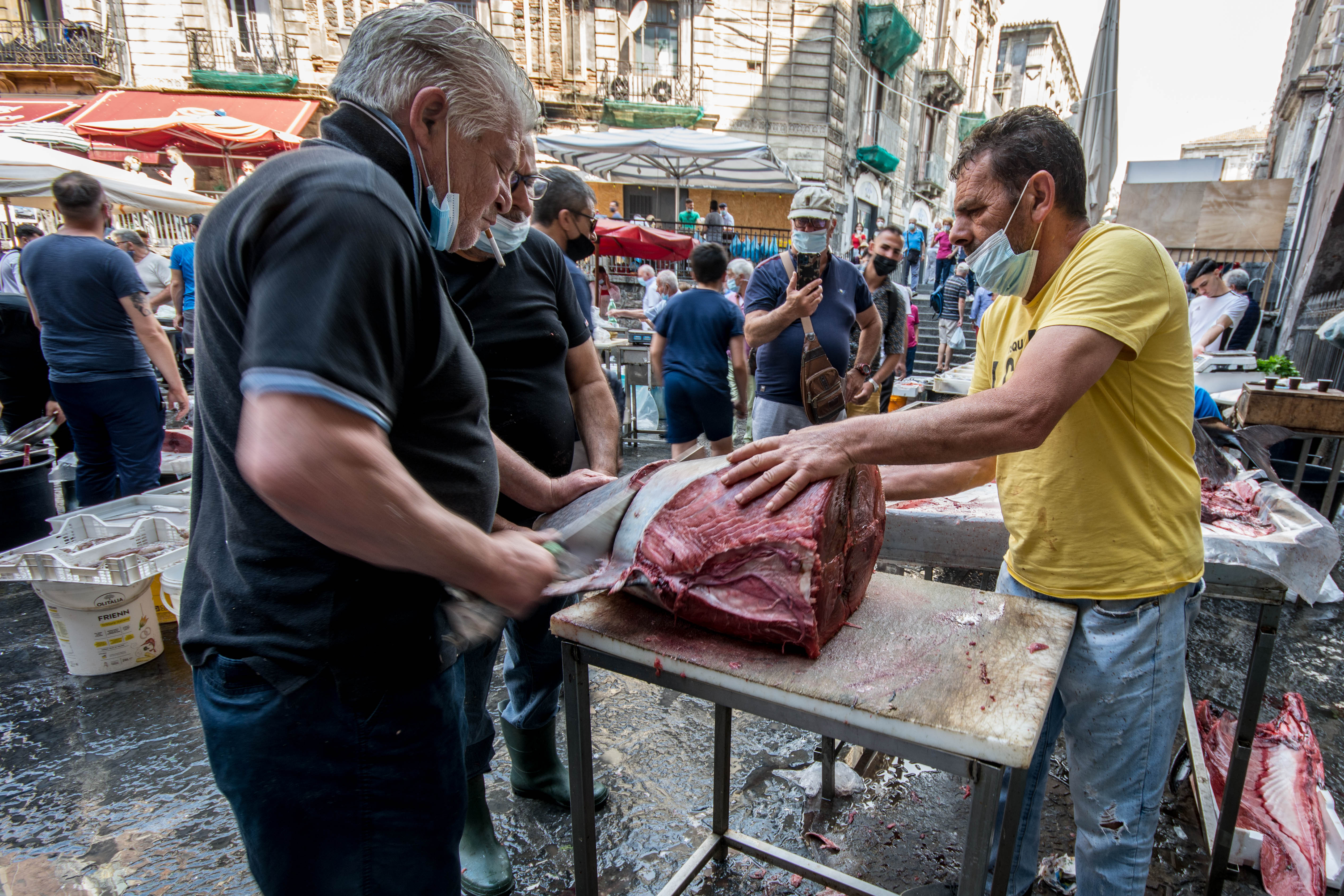 Vendors butchering a large fresh tuna at the La Pescheria fish market in Catania, Sicily