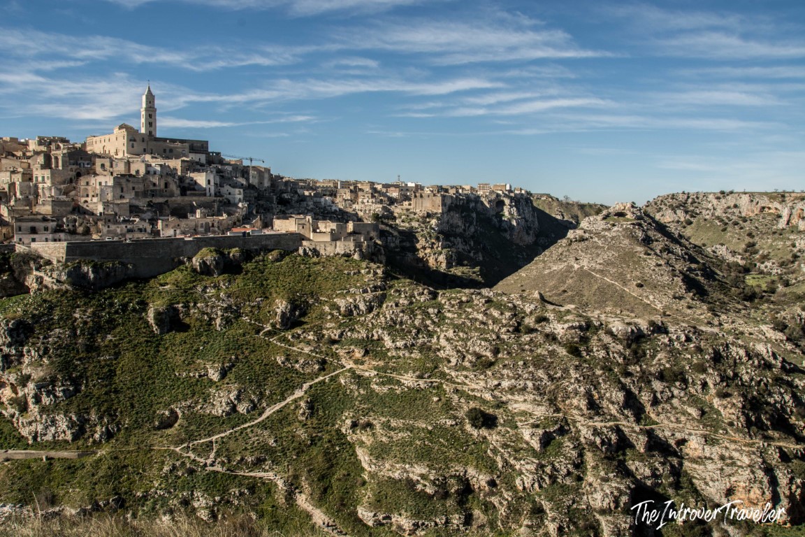 Panoramic view of Matera Sassi district perched on rocky ravine cliffs, with the cathedral bell tower visible