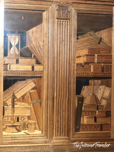 Intarsia wood panels in the Studiolo of Federico da Montefeltro showing shelves with books and an hourglass