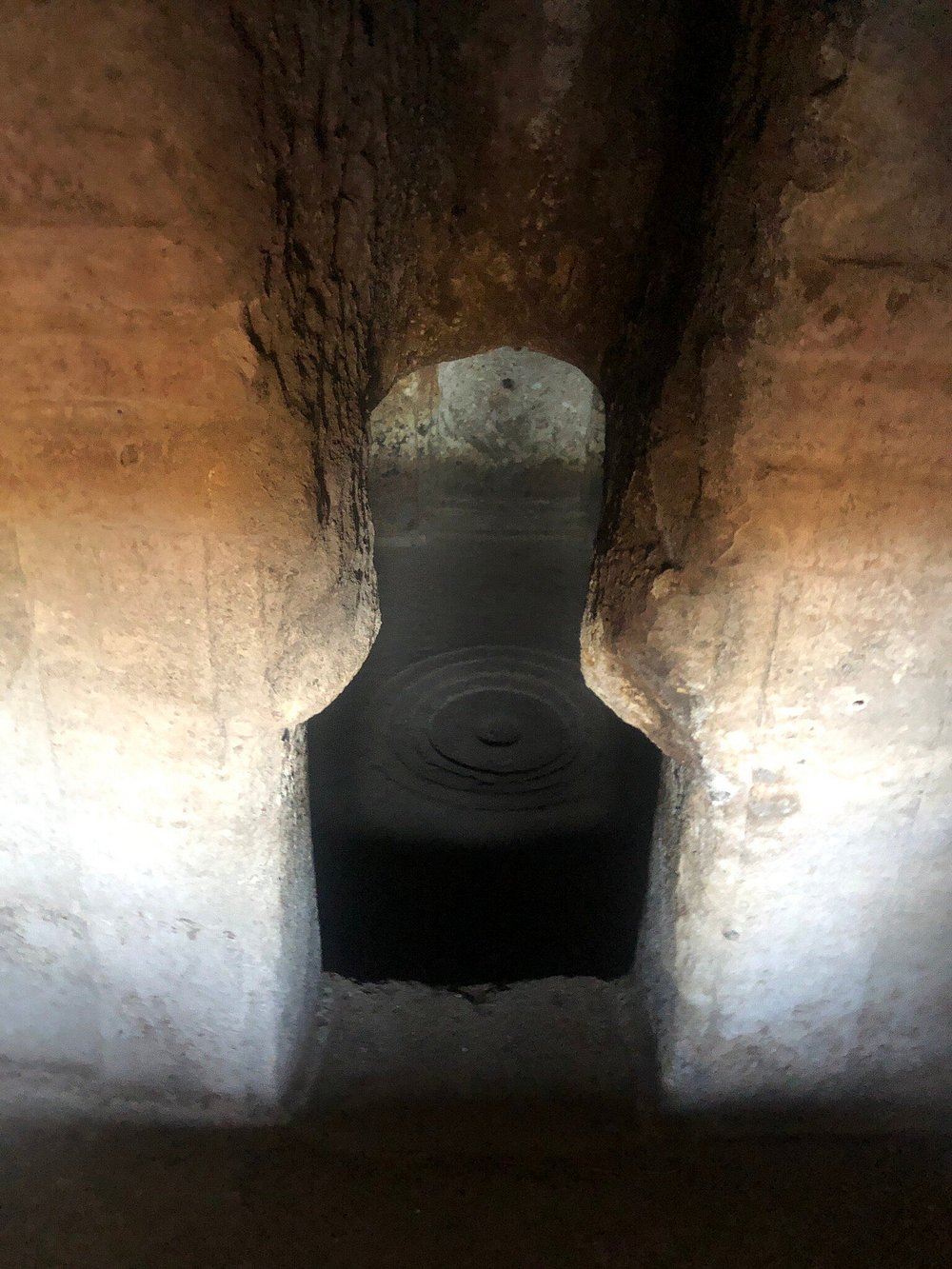 Interior view of an ancient stone tomb at Mont'e Prama, Sardinia, showing a carved burial shaft and arched passage
