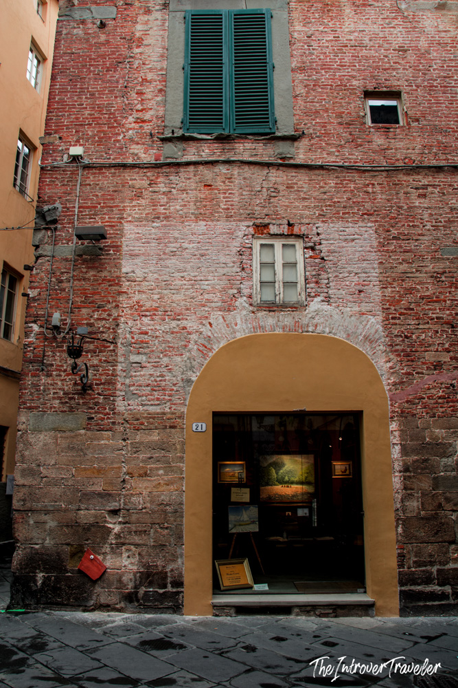 Rustic art gallery in a medieval brick building on a narrow street in Lucca, Tuscany