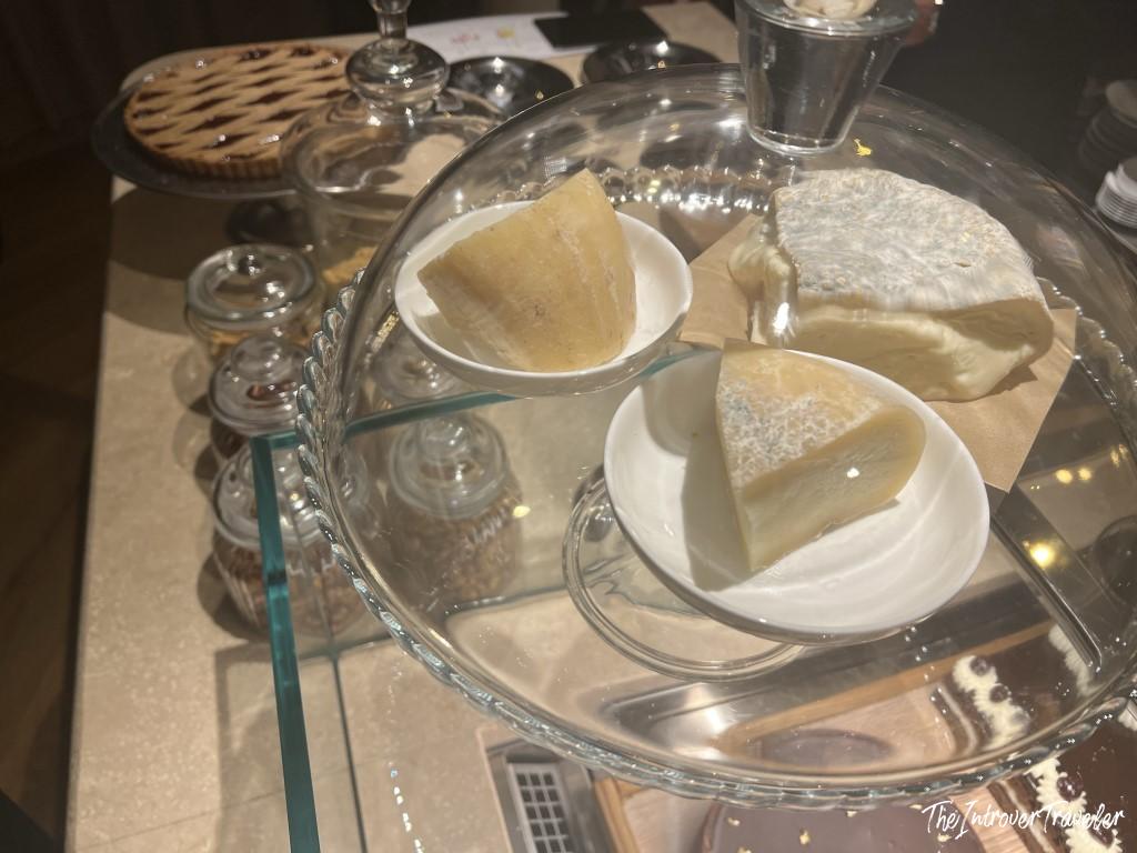 Italian cheese selection on a glass tray at Trattoria Da Lucio, Rimini, including aged Parmigiano and soft-rind varieties.