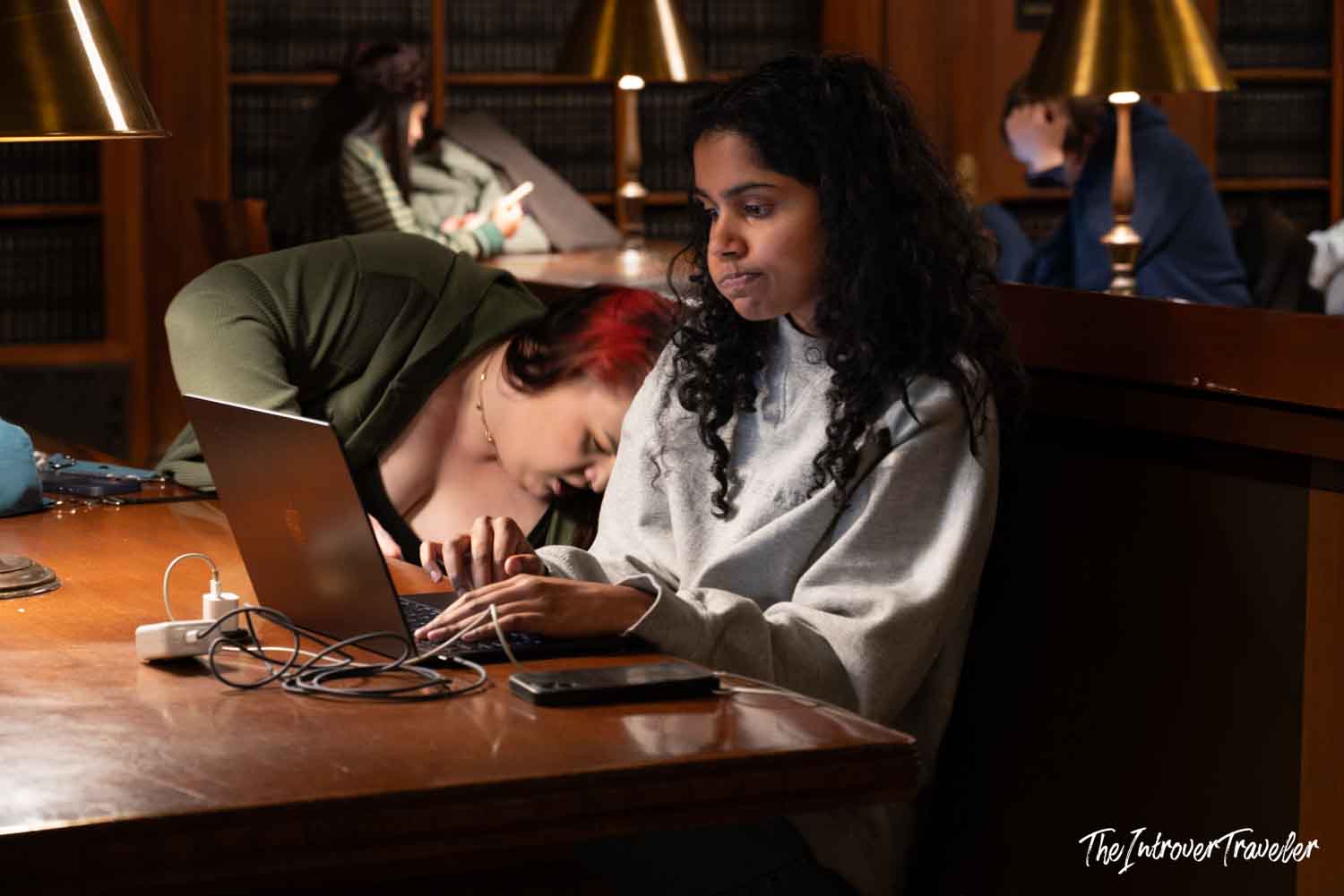 Students studying by laptop at a reading desk inside the New York Public Library