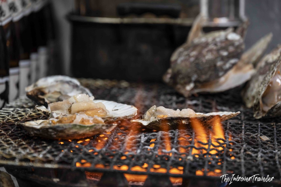 Fresh oysters grilling over open flames at Tsukiji fish market, Tokyo