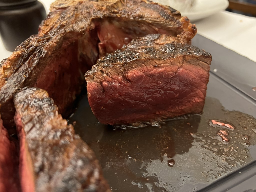 Thick-cut bistecca alla Fiorentina sliced open revealing a rare red center, served at Il Latini Florence