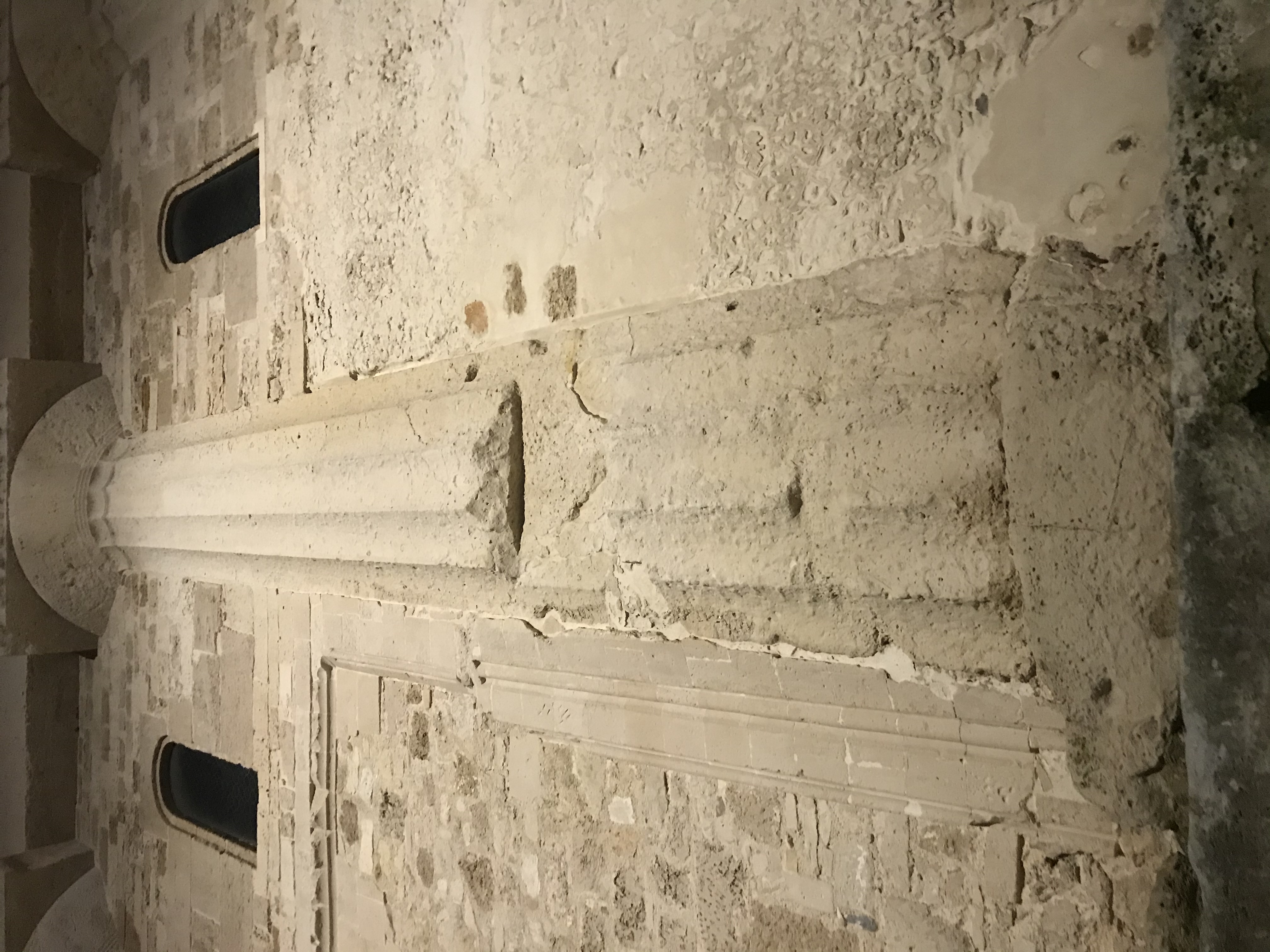 Ancient limestone column and weathered stone wall detail inside a historic church in Ortigia, Syracuse