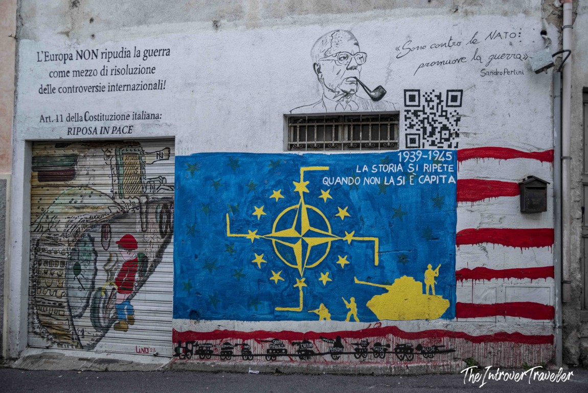 Anti-NATO political mural in Orgosolo, Sardinia, featuring Sandro Pertini quote and EU flag with military symbols