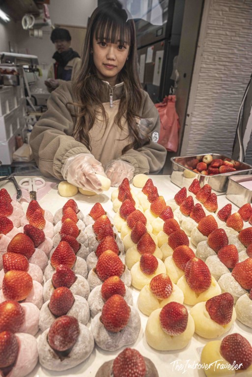 Vendor arranging fresh strawberry daifuku mochi at a Tsukiji market stall in Tokyo