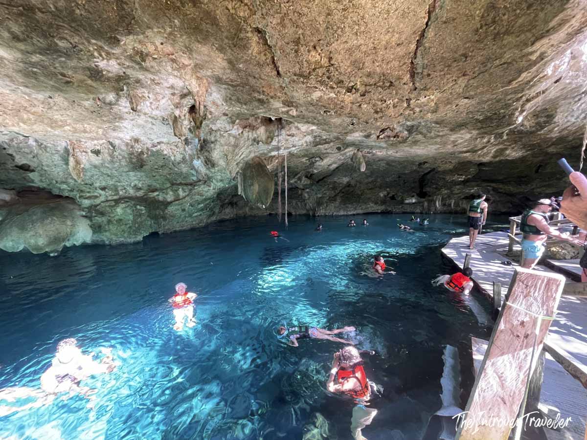 Swimmers in red life vests floating in the crystal-blue waters of Dos Ojos cenote, Yucatan
