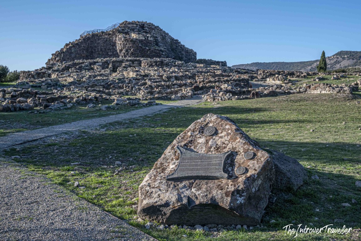 UNESCO heritage plaque stone and the ancient Nuraghe Su Nuraxi tower at Barumini, Sardinia