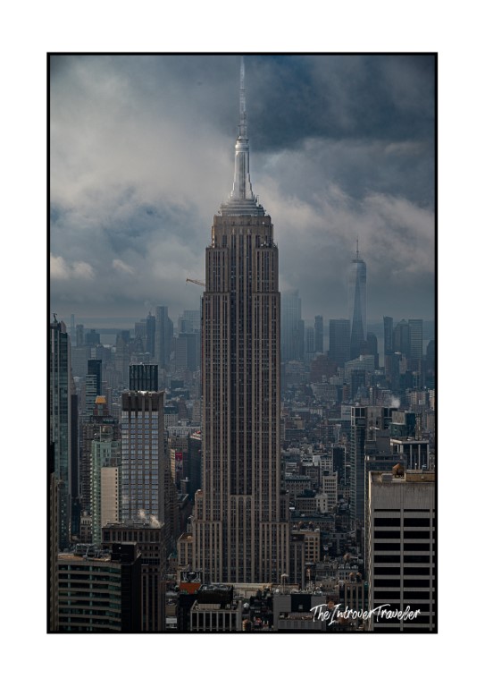 Empire State Building towering over Manhattan skyline, viewed from Top of the Rock under stormy skies