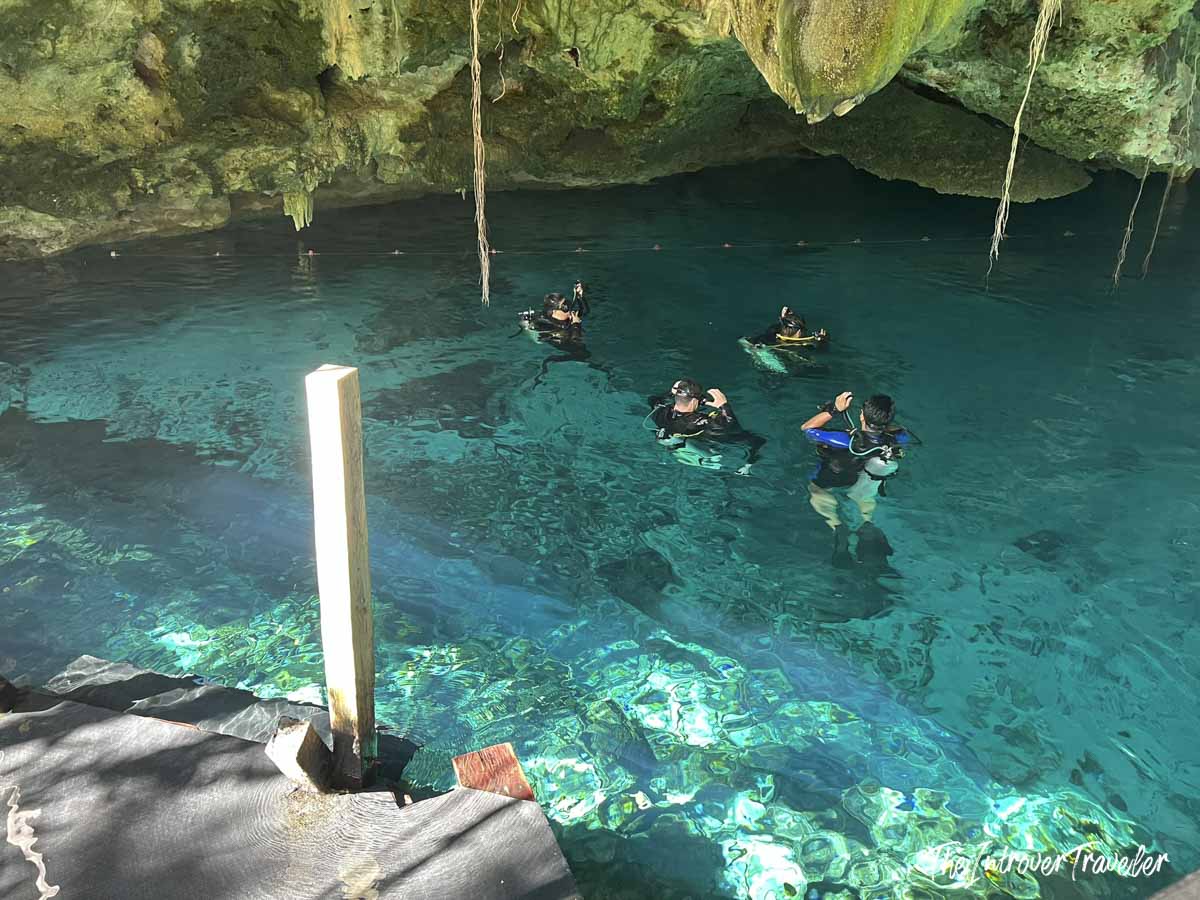 Scuba divers entering the crystal-clear turquoise waters of Dos Ojos cenote, Yucatan Mexico